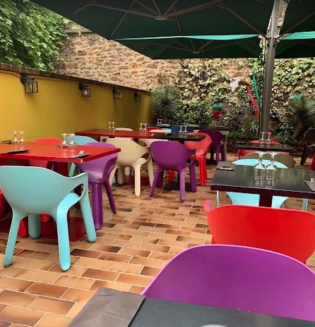 La terrasse color&eacute;e d'El Gringo&nbsp;: chaises bariol&eacute;es, parasols et mur de pierre, 36 places au soleil